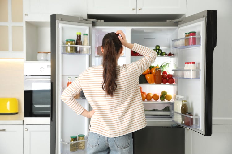 woman looking at her fridge and scratching her head
